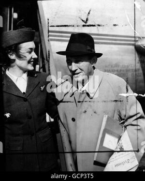 Bing Crosby, still smoking his favourite pipe, talks with Bra Stewardess Thelma Gilland (of Knightsbridge) before leaving Northolt Airport for Paris. Crosby, who made a short stay in England to play a golf match partnered by Bob Hope, is to make a film in France on September 22nd 1952 Stock Photo