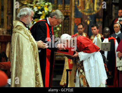 The Archbishop of Canterbury, Rowan Williams watches as Pope Benedict XVI kisses the Canterbury Gospels during a Celebration of Evening Prayer, at Westminster Abbey in central London on the second day of his State Visit. Stock Photo