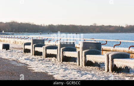 Benches near sea covered with thick ice layer in winter Stock Photo