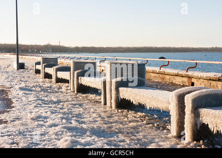 Benches near sea covered with thick ice layer in winter Stock Photo