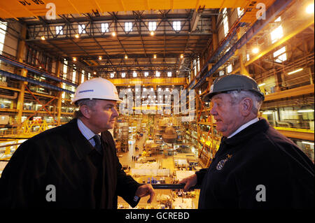 Terry Spurling (right) a former engineer officer of the watch who served on HMS Dreadnought for more than seven years and Tony Burbridge who works on the Astute class subs, stand near the construction of the Ambush submarine at the BAE Systems in Barrow-in Furness. Stock Photo