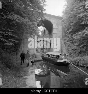 A pleasure-trip narrow boat plies along the Shropshire Union Canal as it is towed beneath a curious double bridge carrying the Newport to Eccleshall Road, near Gnosall, Staffordshire Stock Photo