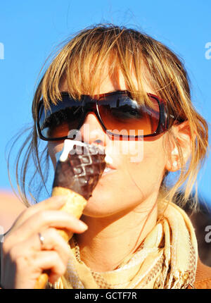 A woman eats an ice cream on Westminster Bridge in London in the warm Autumn sun. Stock Photo