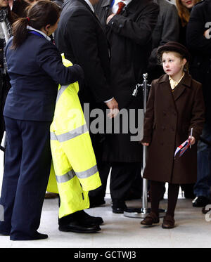 6-year-old Katherine Ashbourne from Brentwood in Essex, is offered a coat to keep her warm while she waits for Queen Elizabeth II outside KPMG's new offices in London's Docklands. Stock Photo