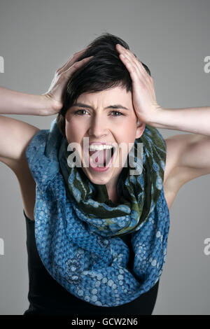 Close up portrait of screaming young short hair girl expression over gray studio background Stock Photo