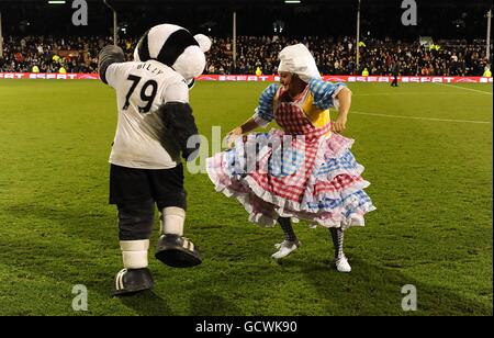 Fulham mascot Billy the Badger (left) dances with Pantomime Dame Sarah the Cook (aka Shaun Prendergast) at half-time Stock Photo