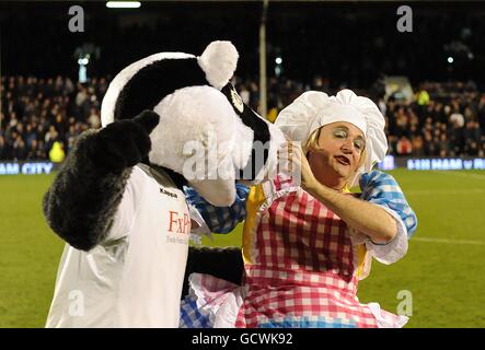 Fulham mascot Billy the Badger (left) with Pantomime Dame Sarah the Cook (aka Shaun Prendergast) at half-time Stock Photo