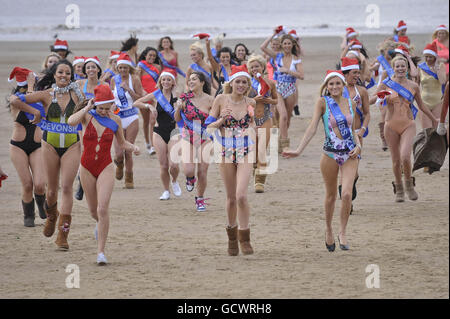 Finalists of the Miss Great Britain beauty pageant run on the beach beside Weston-super-Mare Pier in -2 degrees C wearing one piece swimsuits. Stock Photo