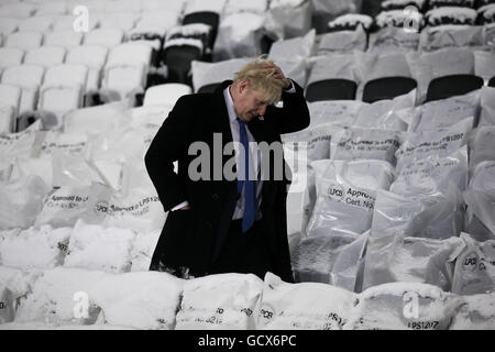 Mayor of London Boris Johnson walks past snow covered seats after the Olympic Stadium floodlights were officially switched on by Prime Minister David Cameron at the Olympic Park in Stratford, London. Stock Photo