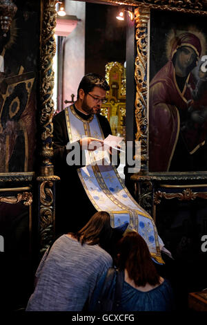A Romanian Orthodox priest gives blessings to believers inside St. Antony's Orthodox Church, known as the Church of the Annunciation ( Biserica Sfantul Anton ) in the old city of Bucharest, Romania Stock Photo