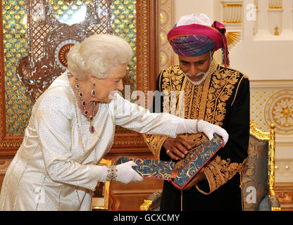 Queen Elizabeth II presents the Sultan of Oman, His Majesty Sultan Qaboos bin Said with a book , before a State Banquet at his Palace in Muscat, Oman. Stock Photo