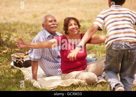 Old people, senior couple, elderly man and woman. Outdoor family having fun with happy grandpa and grandma hugging boy at picnic Stock Photo