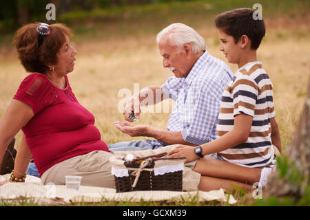 Old people, senior couple, elderly man and woman in park. Sick grandpa taking prescription drugs, medicine, pills for heart care Stock Photo