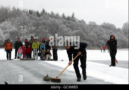 Nigel Holl sweeps a stone during the Stanley Cup curling match Between Blair Drummond Curling club and Port of Menteith Curling Club held on a frozen Lake of Menteith. Stock Photo