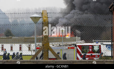 Specialist prison officers escort fire fighters at HMP Ford near Arundel, West Sussex after about 40 prisoners began a riot and set alight the open prison, according to the Ministry of Justice. Stock Photo