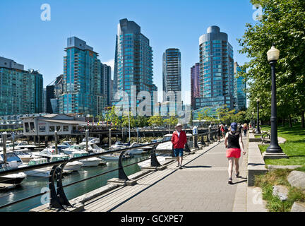 People walking along seawall in Coal Harbour neighbourhood of Vancouver, BC, Canada. Vancouver city skyline and waterfront. Stock Photo