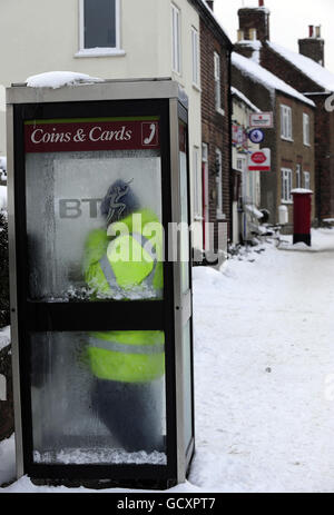 A man uses a telephone box in Topcliffe, near Thirsk in North Yorkshire. The village recorded a temperature of -19C earlier today, the coldest temperature recorded in Yorkshire since records began. Stock Photo