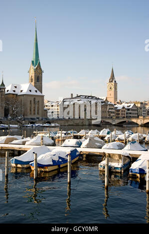 Snow-covered boats at the Limmatquai quay, in the back the Frauenmuenster church, St. Jakobs Kirche church and Muensterbruecke Stock Photo