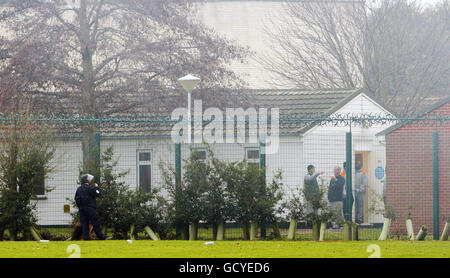 PLEASE NOTE THAT FACES HAVE BEEN PIXELATED BY THE PRESS ASSOCIATION TO PROTECT INMATES IDENTITY A specialist prison office dog handler watches inmates from outside the perimeter fence at HMP Ford near Arundel, West Sussex after about 40 prisoners began a riot and set alight buildings in the open prison, according to the Ministry of Justice. Stock Photo