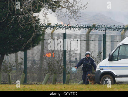 A specialist prison office dog handler patrols outside the perimeter fence at HMP Ford near Arundel, West Sussex after about 40 prisoners began a riot and set alight buildings in the open prison, according to the Ministry of Justice. Stock Photo