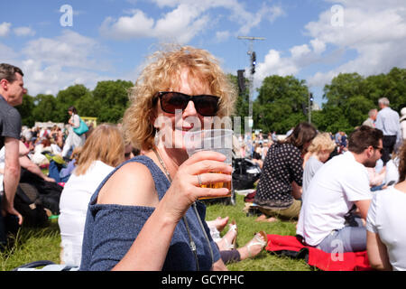 Woman enjoying a pint of beer outside in a plastic glass in summer UK Stock Photo