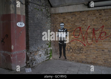 Rude street art graffiti of Damien Hirst on a wall outside his gallery in Vauxhall in London, United Kingdom. Newport Street Gallery presents exhibitions of work from Damien Hirsts art collection. Exhibitions vary between solo and group shows. Stock Photo