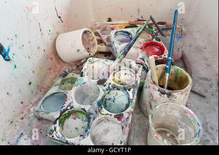 discarded left behind dirty paint brushes in butlers sink needing a serious clean and polish after messy art students painters Stock Photo