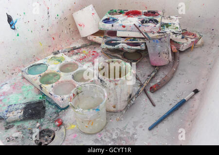 discarded left behind dirty paint brushes in butlers sink needing a serious clean and polish after messy art students painters Stock Photo