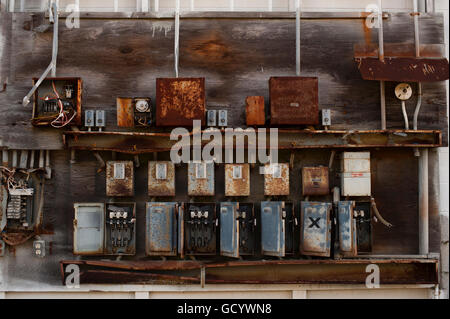 Electrical boxes outside on side of building rusting, damaged and dangerous Stock Photo