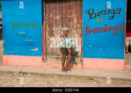An old Cuban woman walking along the cobbled streets of Trinidad towards a Bodega in Cuba Stock Photo