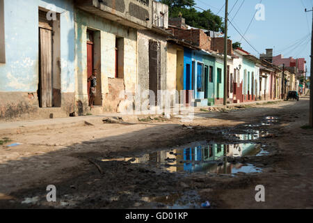 A young boy peers from the doorway of his home in the poor back streets of Trinidad Cuba Stock Photo