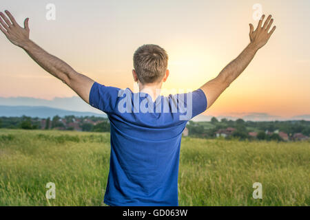 Young happy man in a field of wheat at sunset Stock Photo