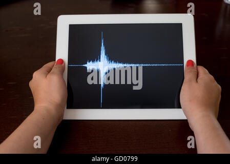 Woman hand pointing a blue earthquake with a black background on a white tablet Stock Photo