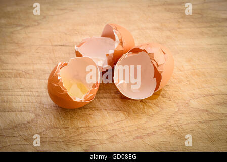 Three broken eggshells on a wooden board Stock Photo