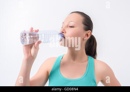 Woman drinking water from bottle on a white isolated background Stock Photo