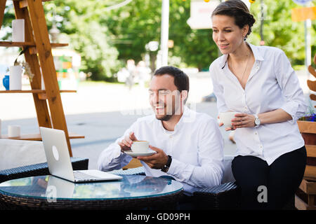 Business colleagues with a laptop working in outdoors cafe using conference internet call Stock Photo