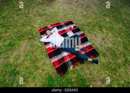 Happy young man with laptop relaxing on the grass, view from the top Stock Photo