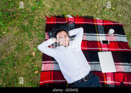 Happy young man with laptop relaxing on the grass, view from the top Stock Photo