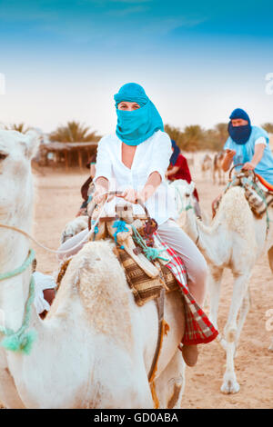 Young caucasian woman tourist riding on camel in Sahara desert. Tunis Stock Photo