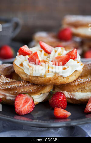 Cream puff rings (choux pastry) decorated with fresh strawberry and caramel sauce Stock Photo