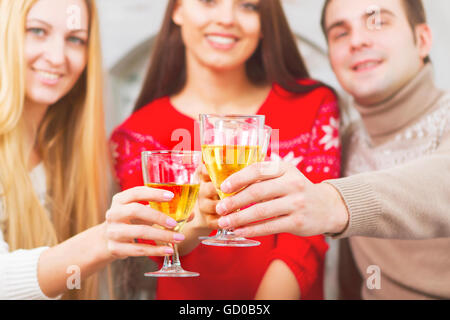 Young happy smiling friends drinking champagne by the Christmas tree Stock Photo