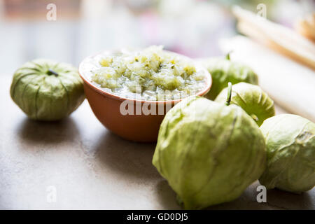 Tomatillos and  a bowl of green salsa on stone surface. Stock Photo