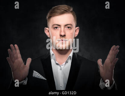 Man covering his ears over dark background. Stock Photo