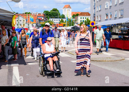 Ronneby, Sweden - July 9, 2016: Big public market day in town with lots of people. Here a female person in a wheelchair is pushe Stock Photo