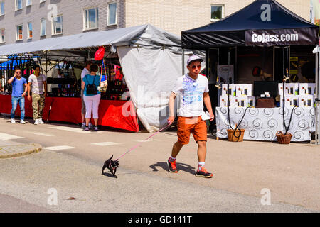 Ronneby, Sweden - July 9, 2016: Big public market day in town with lots of people. Here a young man is walking by with a very sm Stock Photo