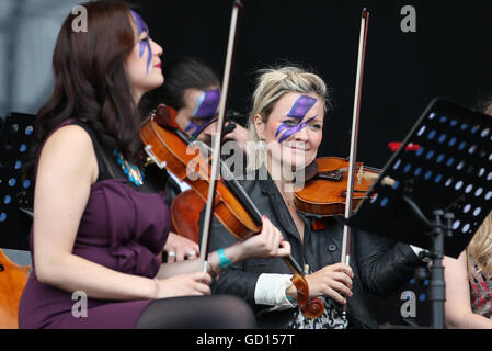 Members of the Rogue Orchestra with faces painted like Ziggy Stardust perform a David Bowie tribute set on the main stage during the third day of T in the Park, the annual music festival held at Strathallan Castle, Perthshire. Stock Photo