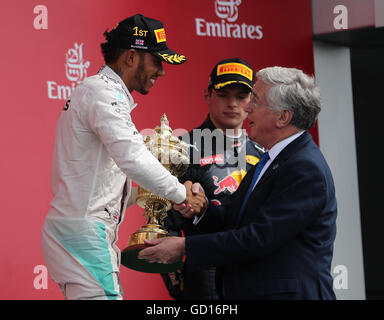 Mercedes' Lewis Hamilton is presented the trophy by Michael Fallon, Secretary of State for Defence after the 2016 British Grand Prix at Silverstone Circuit, Towcester. Stock Photo