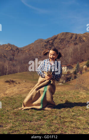 Little girl jumps with a lot of potatoes outdoors Stock Photo