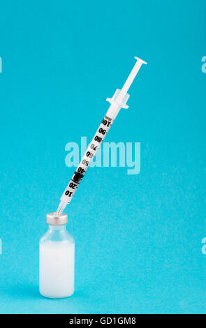 Insulin bottles(s) and syringe against a blue background Stock Photo