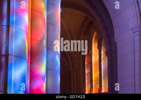 Light streaming through stained glass windows with colourful light columns along the cathedral nave Stock Photo